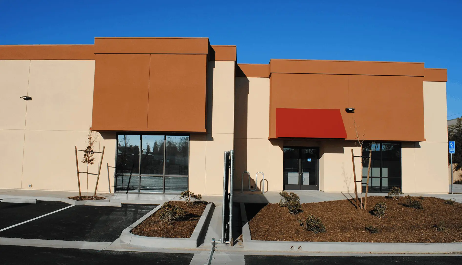 A building with two windows and a red awning.