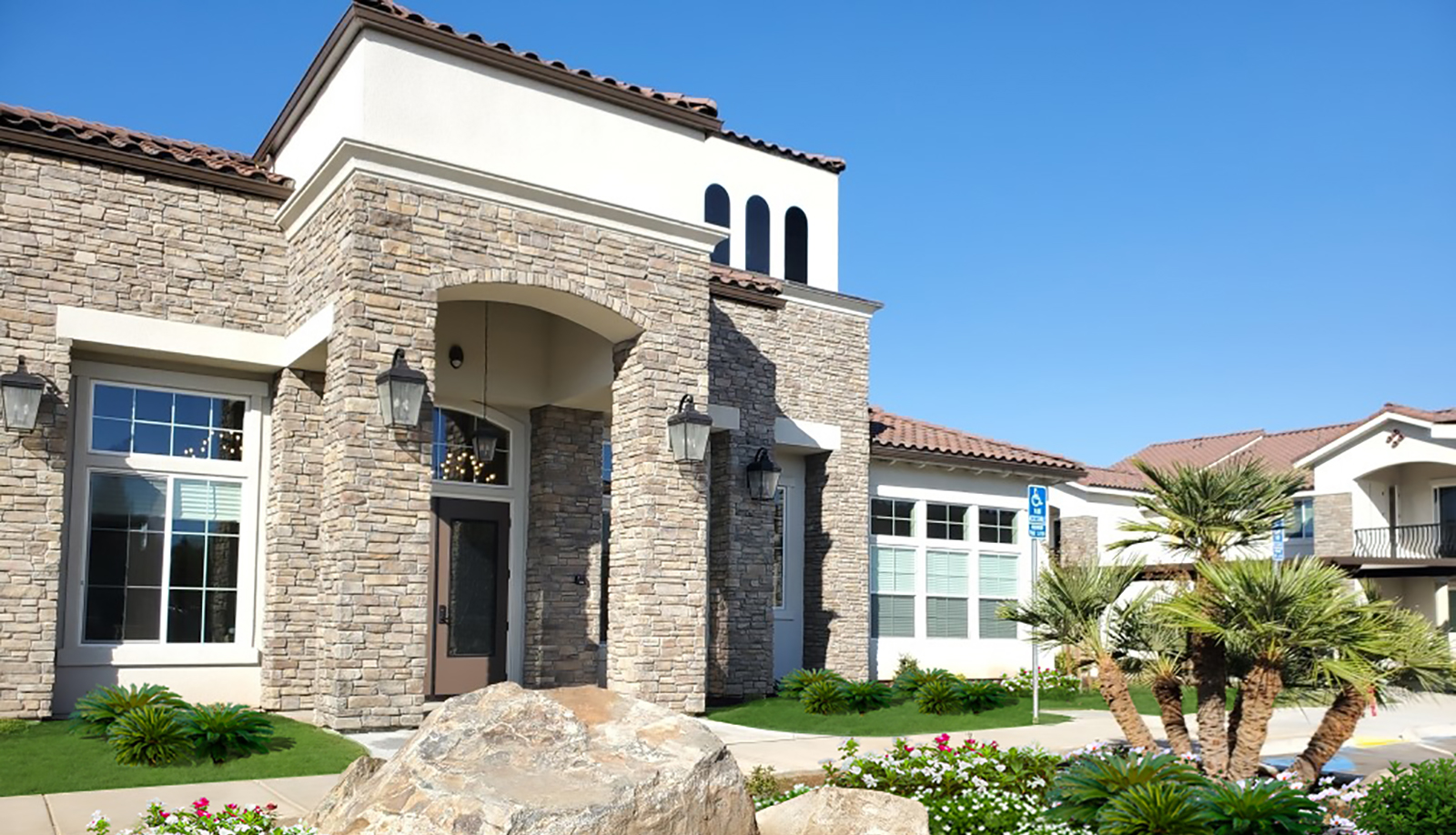 A large building with a stone facade and a rock wall.